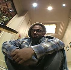 a man sitting on the ground in front of a stair case with his arms crossed