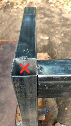 there is a metal object with a red x on the end and a piece of wood behind it