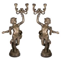 a pair of bronze figurines with candlesticks on their heads and arms