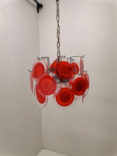 a red chandelier hanging from a ceiling in a room with white walls and flooring