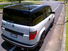 the back end of a white van parked on the side of a road next to grass and trees