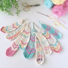 several crocheted feathers sitting on top of a table next to yarn and scissors