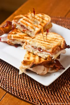 two grilled sandwiches on a plate with toothpicks sticking out of the top