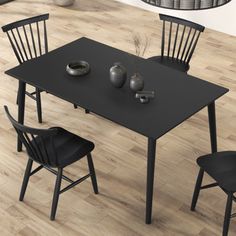 a black dining table with four chairs and a vase on the floor next to it