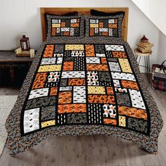 a bed with an orange and black quilt on it