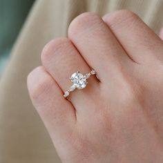 a woman's hand with a diamond ring on top of her finger, showing the center stone