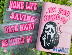 two pink notebooks with stickers on them sitting next to each other in the grass