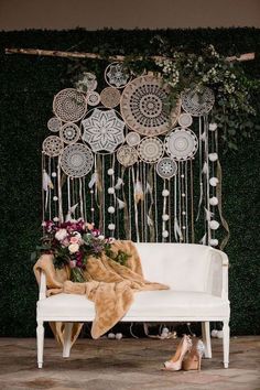 a white couch sitting in front of a green wall with flowers and feathers hanging from it