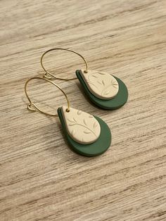 two green and white earrings sitting on top of a wooden table next to each other