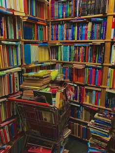 the bookshelves are filled with many different types of books and there is a shopping cart in front of them