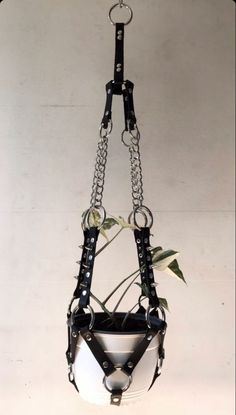 a white and black planter hanging from a metal chain with chains attached to it