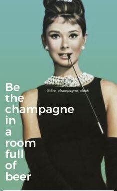 a woman in a black dress with a pin on her nose and the caption be the champagne in a room full of beer