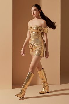 a woman in gold dress and knee high boots