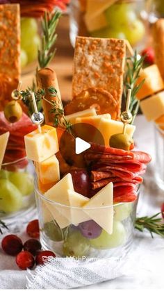 an assortment of cheeses, crackers and olives in small glass bowls on a table