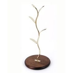 a metal plant on a wooden stand with a white base and gold leaf decoration in the shape of a twig