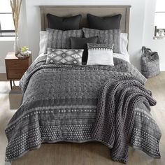 the bed is made with black and white comforters, pillows, and throw blankets