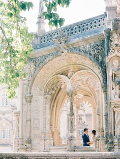 a bride and groom are sitting on the balcony of an old building with stone arches