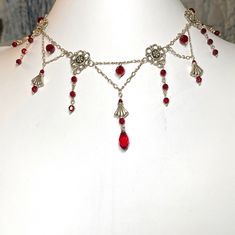 Elegant Victorian gothic style choker necklace of sterling silver chain, antique silver links, and red Swarovski crystals.  Center long dangle is about 2 1/2 inches long.  The necklace is 13 1/2 inches long, fastens with a sterling silver fish hook clasp, and comes nestled comfortably on a bed of cotton in a white cardboard jewelry box.  NA-588-C25 Gothic Red Jewelry With Lobster Clasp, Red Gothic Jewelry With Lobster Clasp, Gothic Red Jewelry With Chain, Red Gothic Jewelry With Chain, Gothic Red Chain Jewelry, Victorian Gothic Style, Cardboard Jewelry, Edgy Jewelry, Medieval Jewelry