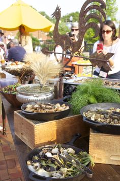 several plates of food on a table with people in the background at an outdoor event