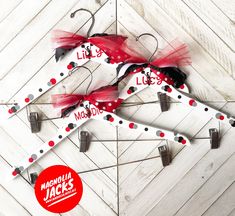 two red and black metal scissors with personalized name tags attached to them on white wood planks