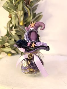 a small glass vase with a purple hat on top