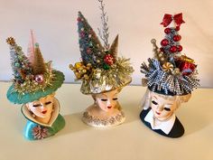 three masks with christmas decorations on them sitting next to each other in front of a white wall