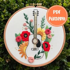 an embroidered guitar with flowers and leaves on it is displayed in front of some bushes