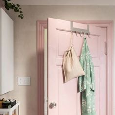 a pink door with two towels hanging from it's hooks and a bag on the handle