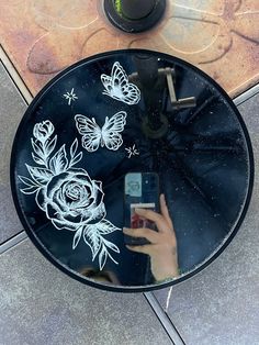 a person holding a cell phone in front of a glass table with flowers on it