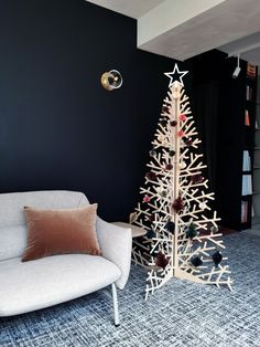 a white couch sitting next to a wooden christmas tree