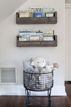 two shelves with books and stuffed animals on them in the corner of a white room