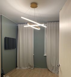 an empty room with curtains and a television mounted on the wall in front of it