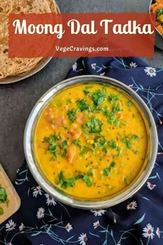 a bowl filled with yellow soup next to two plates of food on a blue table cloth