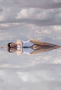 a woman is floating in the water with her reflection