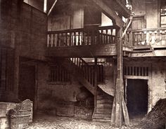 an old black and white photo of a house with stairs to the second floor, next to a wicker basket