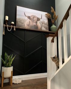 two cats are sitting on the stairs in front of a painting and potted plant