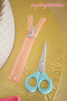 two pairs of scissors are sitting on a gold plate with pink and blue trimmings