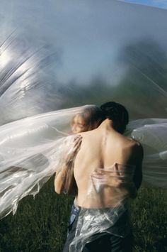 a man and woman wrapped in plastic are walking through the grass with their arms around each other