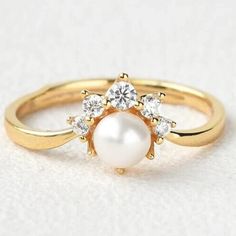 a gold ring with white pearls and diamonds on the side, in front of a white background