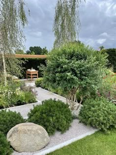 a garden with rocks and plants in the center, surrounded by greenery on both sides