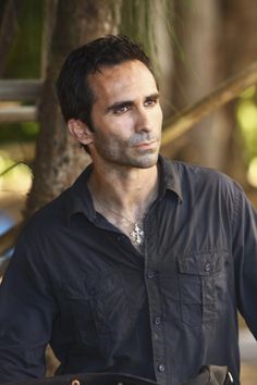 a man in black shirt standing next to a tree