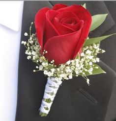 a red rose boutonniere with baby's breath in the lapel