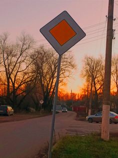 an orange and white sign sitting on the side of a road next to a lush green field