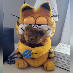 a stuffed animal that looks like garfield the cat is holding another stuffed animal in his arms