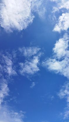 the airplane is flying high in the blue sky with white clouds above it and below