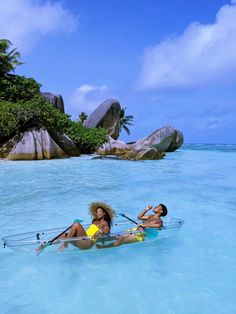 two people in a body of water with paddles on their backs and one person laying down