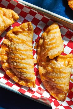 three pastries sitting on top of a red and white checkered tray