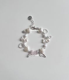 a white bracelet with charms and flowers on the clasp is shown against a plain background