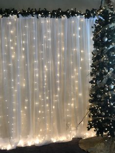 a christmas tree in front of a curtain with lights