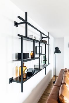 a leather couch sitting in front of a wall mounted shelf with books and other items on it